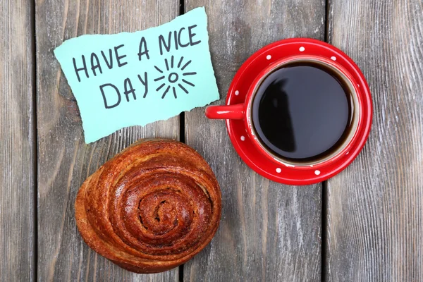 Composition of coffee, fresh bun and paper card on wooden background — Stock Photo, Image