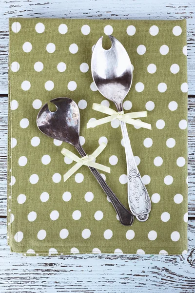 Metal spoons on green polka dot napkin on wooden background — Stock Photo, Image