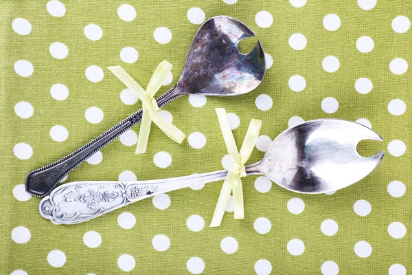 Metal spoons on polka dot fabric background — Stock Photo, Image