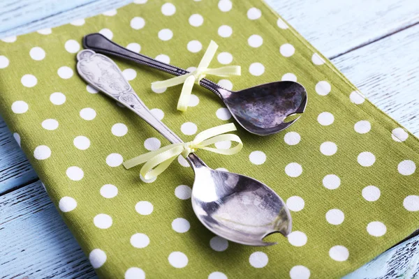 Metal spoons on green polka dot napkin on wooden background — Stock Photo, Image