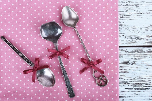 Metal spoons on pink polka dot napkin on wooden background — Stock Photo, Image