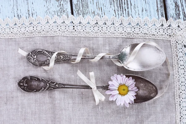 Spoons on lace napkin on wooden background — Stock Photo, Image