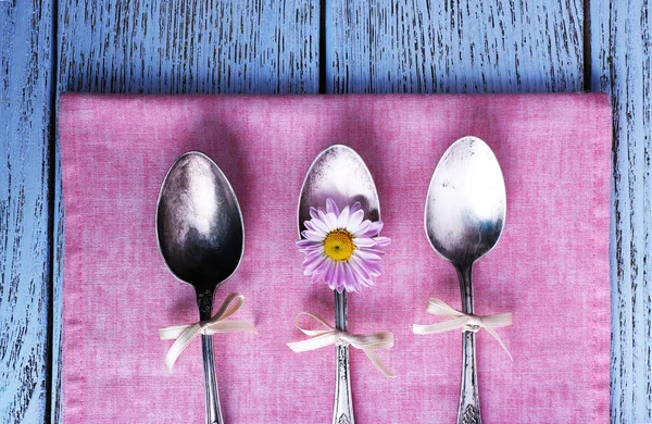Metal spoons on pink napkin on wooden background — Stock Photo, Image
