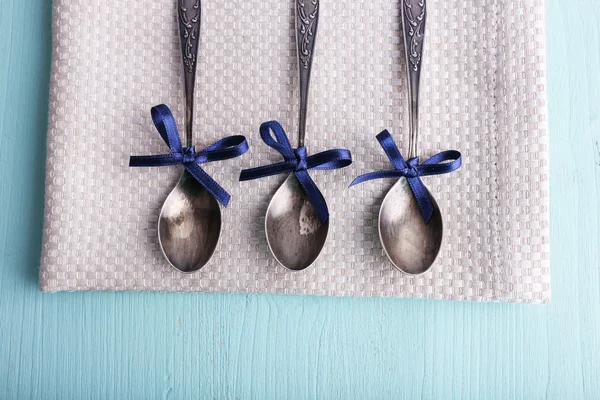 Metal spoons on napkin on light blue wooden background — Stock Photo, Image