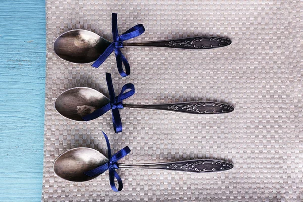 Cucchiai di metallo su tovagliolo su sfondo di legno azzurro — Foto Stock