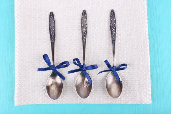 Metal spoons on napkin on light blue wooden background — Stock Photo, Image
