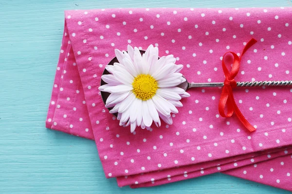 Camomile in metal spoon on pink polka dot napkin on wooden background — Stock Photo, Image