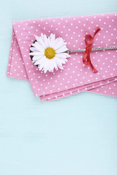 Camomile in metal spoon on pink polka dot napkin on wooden background — Stock Photo, Image