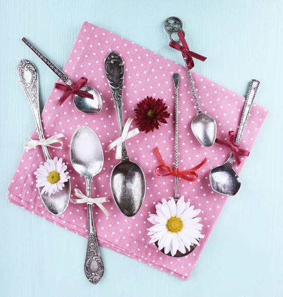 Metal spoons on pink polka dot napkin on wooden background — Stock Photo, Image