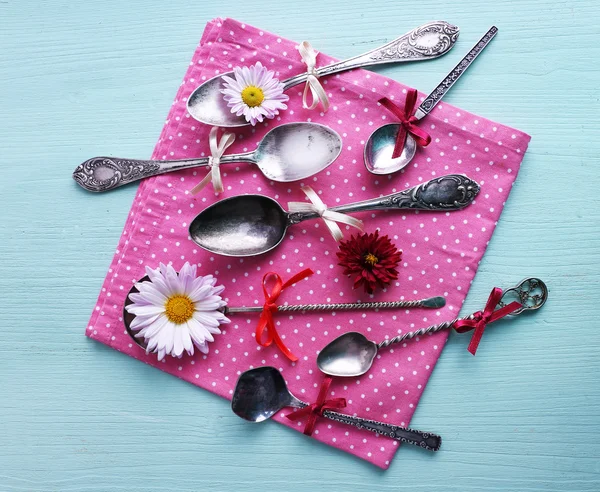 Colheres de metal no guardanapo de bolinhas rosa no fundo de madeira — Fotografia de Stock