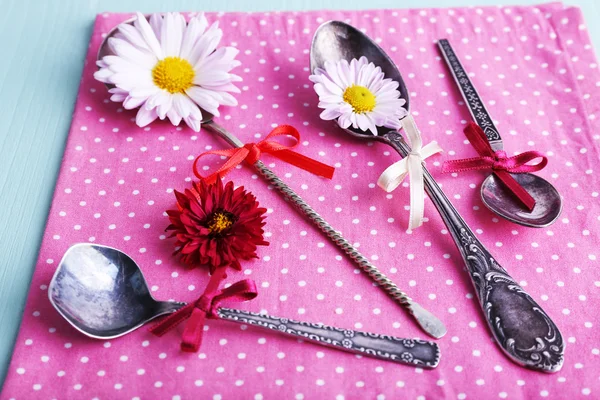 Metal spoons on pink polka dot napkin on wooden background — Stock Photo, Image