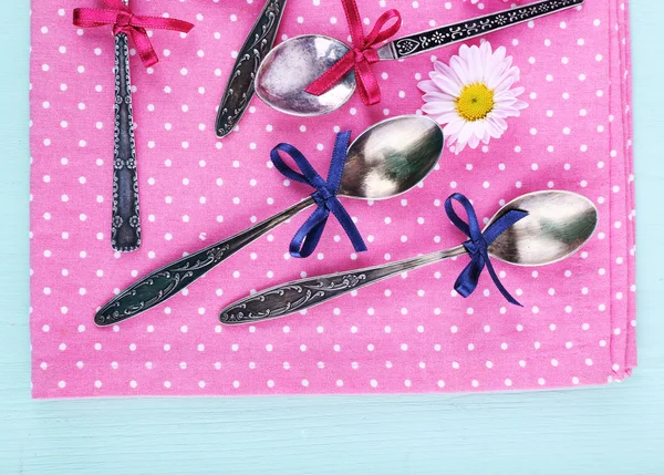 Metal spoons on pink polka dot napkin on wooden background — Stock Photo, Image