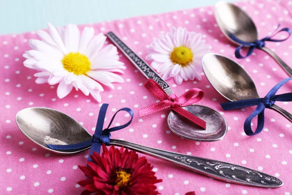 Metal spoons on pink polka dot napkin on wooden background — Stock Photo, Image