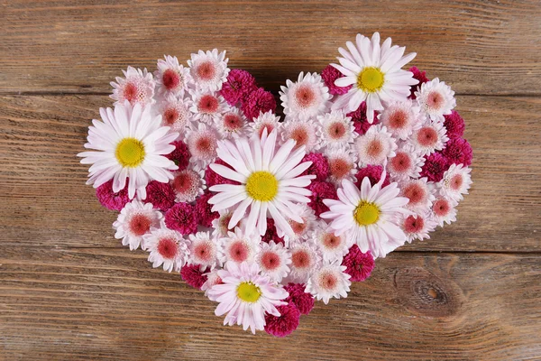 Beautiful flowers in heart shape on wooden background — Stock Photo, Image