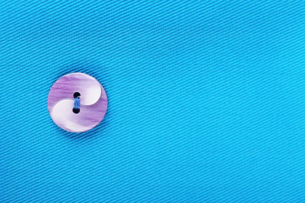 Knopf auf blauem Tuch — Stockfoto
