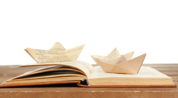 Origami barcos no livro velho na mesa de madeira, no fundo branco — Fotografia de Stock