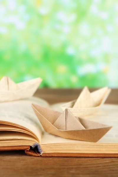 Лодки Оригами на старой книге на деревянном столе, на открытом воздухе — стоковое фото