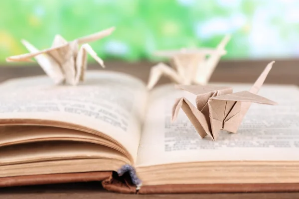 Оригами краны на старой книге на деревянном столе, на открытом воздухе — стоковое фото