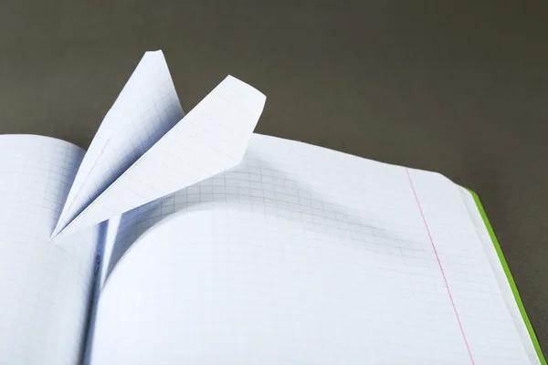 Origami vliegtuig op notebook, close-up — Stockfoto