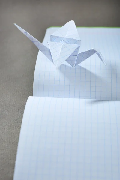 Origami cranes on notebook on grey background — Stock Photo, Image