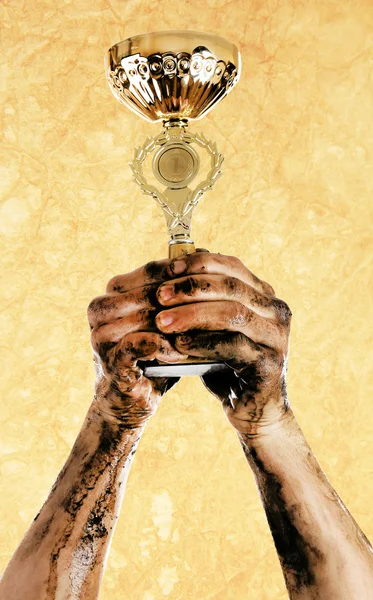 Gold cup in dirty hands — Stock Photo, Image