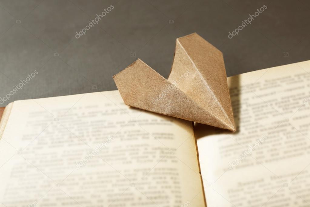 Origami airplane on old book, close up