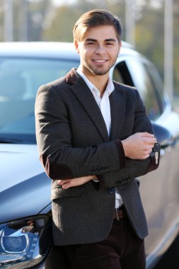 Araba anahtarı açık havada tutan işadamı