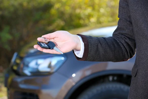 Mano maschile con chiave auto su sfondo auto — Foto Stock