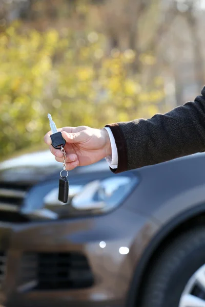 Mão masculina com chave de carro no fundo do carro — Fotografia de Stock