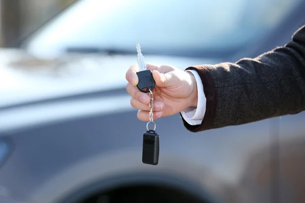 Männliche Hand mit Autoschlüssel auf Auto-Hintergrund — Stockfoto