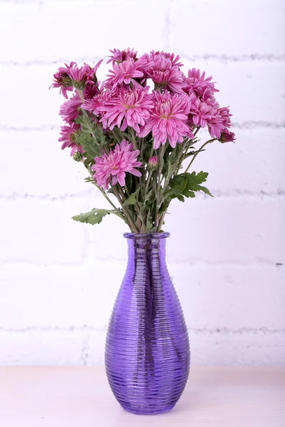 Beautiful vase with flowers on fireplace in room — Stock Photo, Image