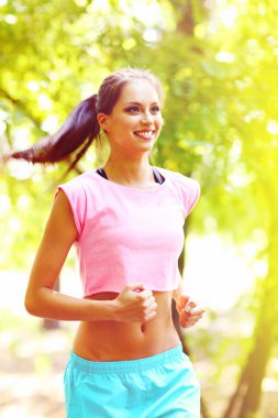 Genç bir kadın parkta koşuyor.