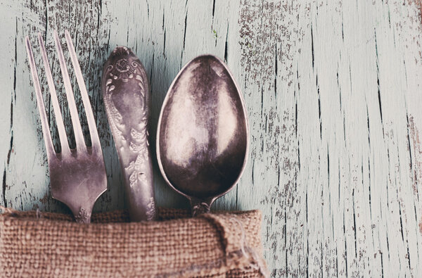 Старая посуда, завернутая во вретище салфетки на деревянном фоне
