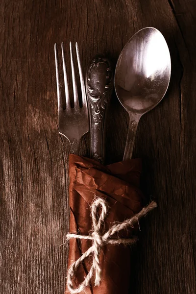 Stary naczynia zawinięte w papier na worze serwetka na drewniane tła — Zdjęcie stockowe
