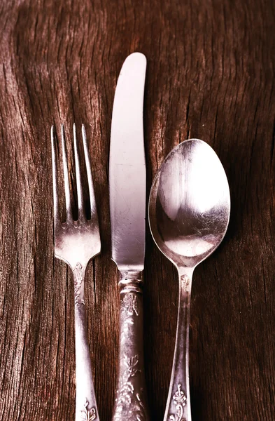 Old metal knife, spoon and fork on wooden background — Stock Photo, Image