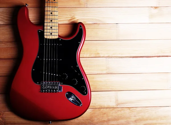 Guitarra roja sobre fondo de madera — Foto de Stock