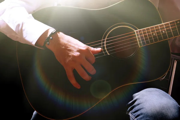 Junger Musiker spielt Akustikgitarre auf dunklem Hintergrund — Stockfoto