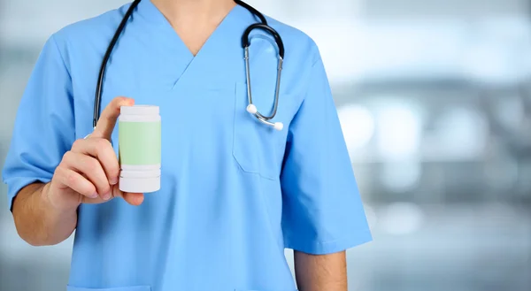 Young male doctor with pills on hospital background — Stock Photo, Image