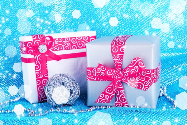 Noel hediye kutuları mavi kumaş arka plan üzerinde kırmızı kurdele ile süslenmiş — Stok fotoğraf