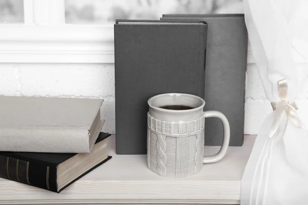 Oude boeken en kopje koffie op de vensterbank — Stockfoto