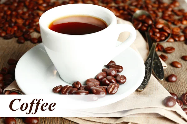 Cup of coffee and coffee beans with chocolate glaze on wooden background — Stock Photo, Image