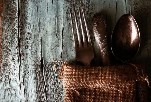 Старая посуда, завернутая во вретище салфетки на деревянном фоне
