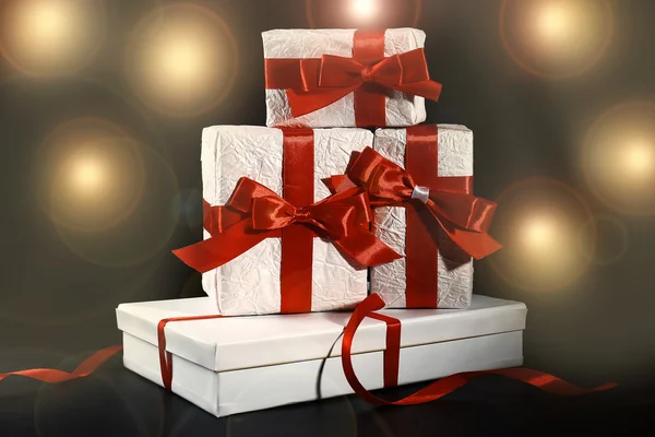 Beautiful gifts with red ribbons, on dark background — Stock Photo, Image