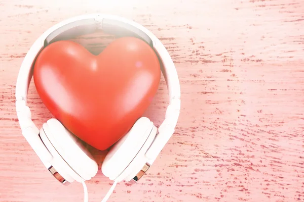 Headphones and heart on color wooden background — Stock Photo, Image