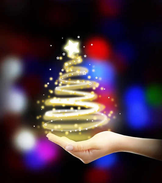 Konsep Natal. Tangan wanita dengan lampu berbentuk pohon cemara pada latar belakang meriah yang mengkilap — Stok Foto