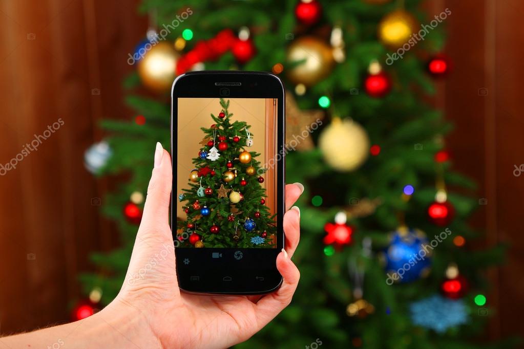 смарт. фотограф фотографирует елочку. наряженная елка размытая. девочки которые фотографируют себя с ёлкой. елка с управлением со смартфона.
