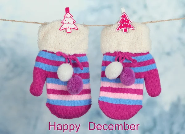 Striped mittens hanging on clothesline as Happy December card — Stock Photo, Image