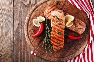 Grilled salmon on cutting board on wooden background clipart