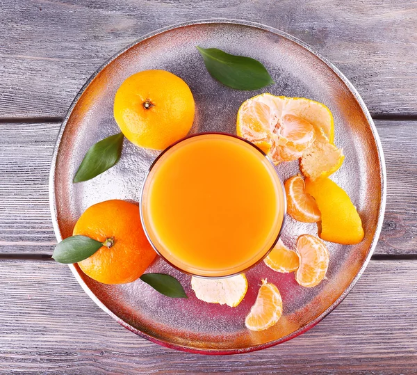 Glass of juice and ripe sweet tangerine on wooden table — Stock Photo, Image