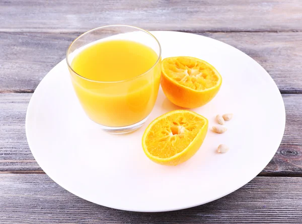 Glass of juice and ripe sweet tangerine on wooden table — Stock Photo, Image